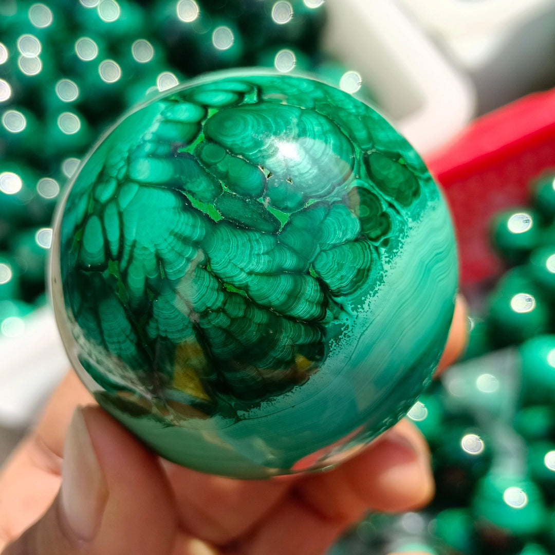 Hand-polished Malachite Crystal Sphere featuring vibrant, swirling forest green bands for heart chakra healing.