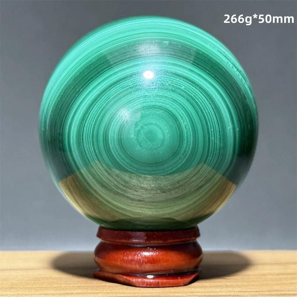 Polished 50mm malachite crystal sphere featuring vibrant green banded patterns on a wooden display base for healing.