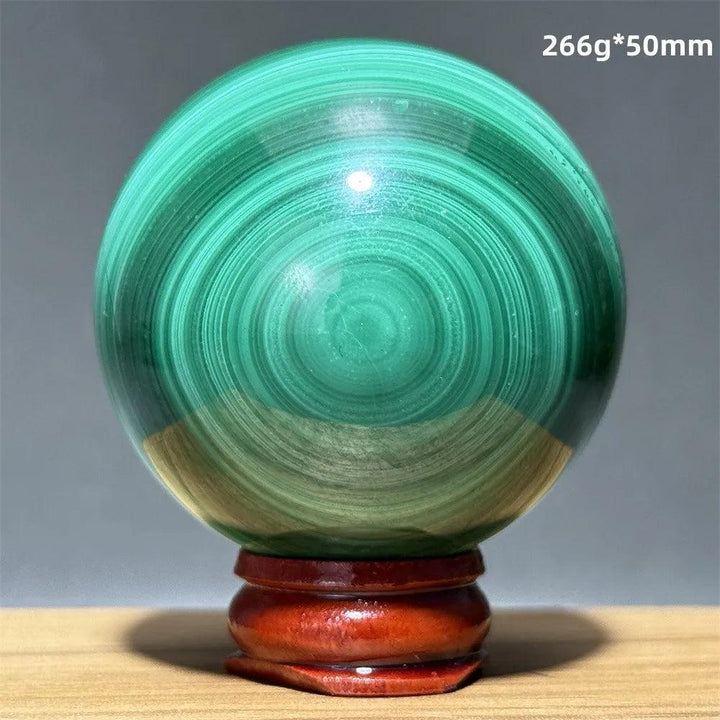 Polished 50mm malachite crystal sphere featuring vibrant green banded patterns on a wooden display base for healing.