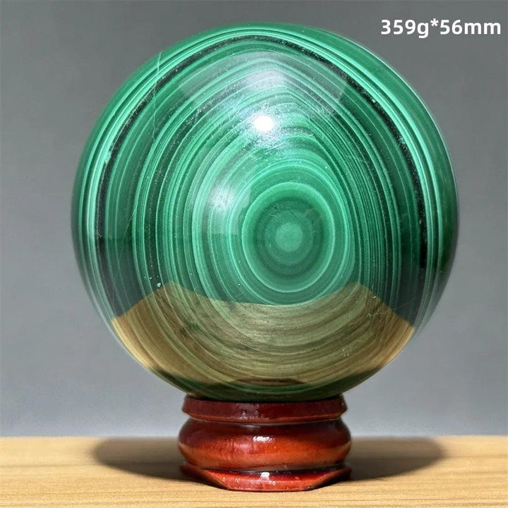 Polished 56mm malachite crystal sphere featuring vibrant green banded patterns on a wooden display base for healing.
