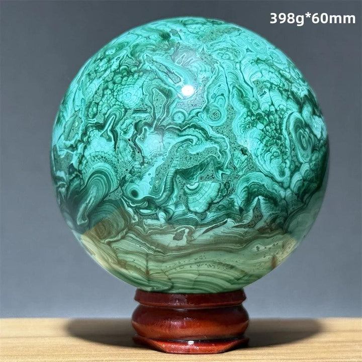 Polished 60mm malachite crystal sphere featuring vibrant green swirling bands on a wooden display base for healing.