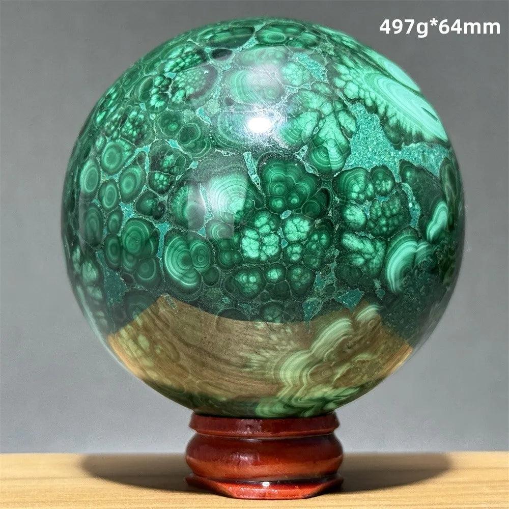 Polished 64mm malachite crystal sphere featuring vibrant green banded patterns on a wooden display base for healing.