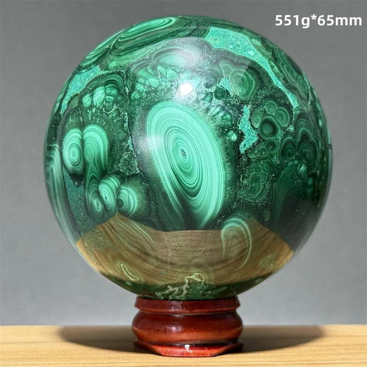 Polished 65mm malachite crystal sphere featuring vibrant green swirling bands on a wooden display base for healing.