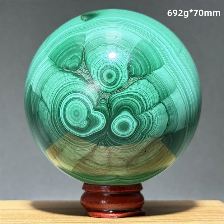 Polished 70mm malachite crystal sphere featuring vibrant green banded patterns on a wooden display base for healing.