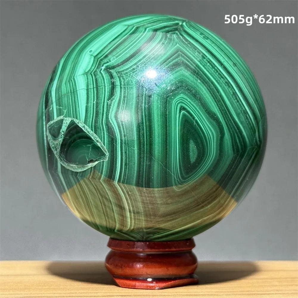 Polished Malachite crystal sphere featuring vibrant green banded patterns on a wooden display base for healing energy.