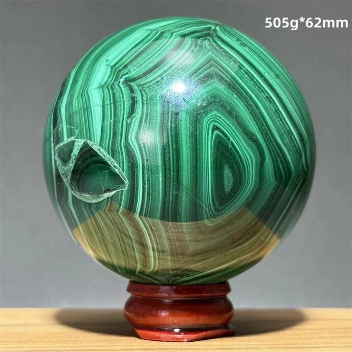 Polished Malachite crystal sphere featuring vibrant green banded patterns on a wooden display base for healing energy.