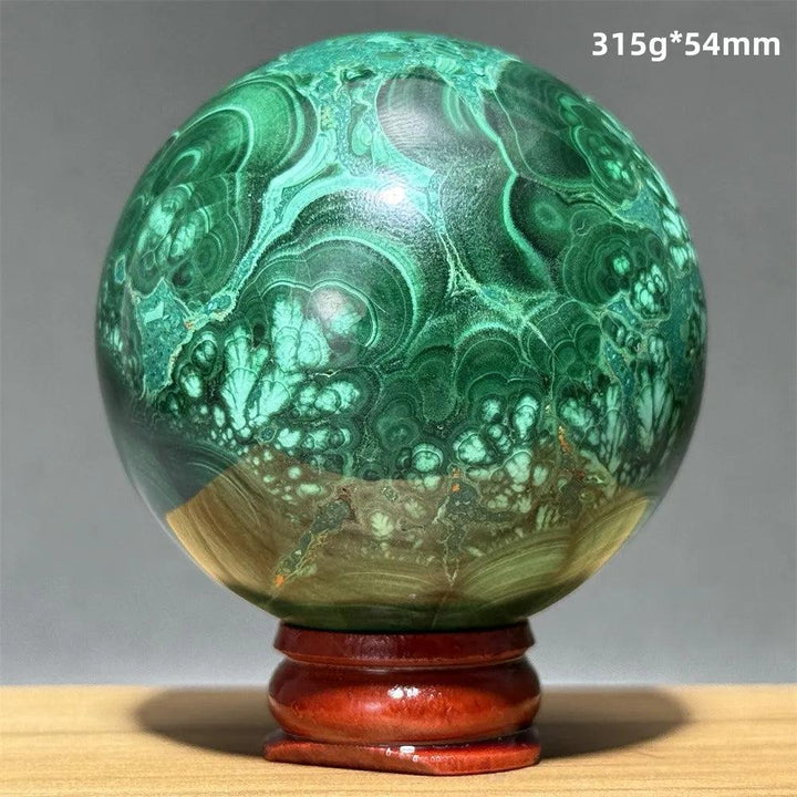 Polished 54mm malachite crystal sphere featuring vibrant green banded patterns on a wooden display base for healing.