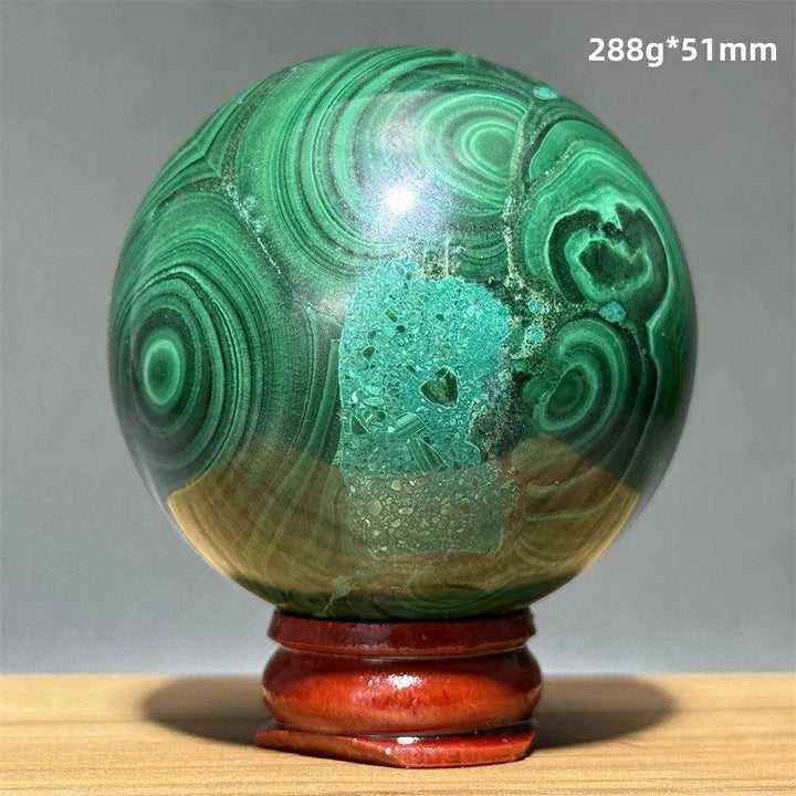 Polished 51mm malachite crystal sphere featuring vibrant green banded patterns on a wooden display base for healing.