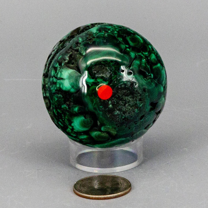 Malachite Sphere, a protective healing crystal with deep forest green and mint concentric rings, on a clear stand.