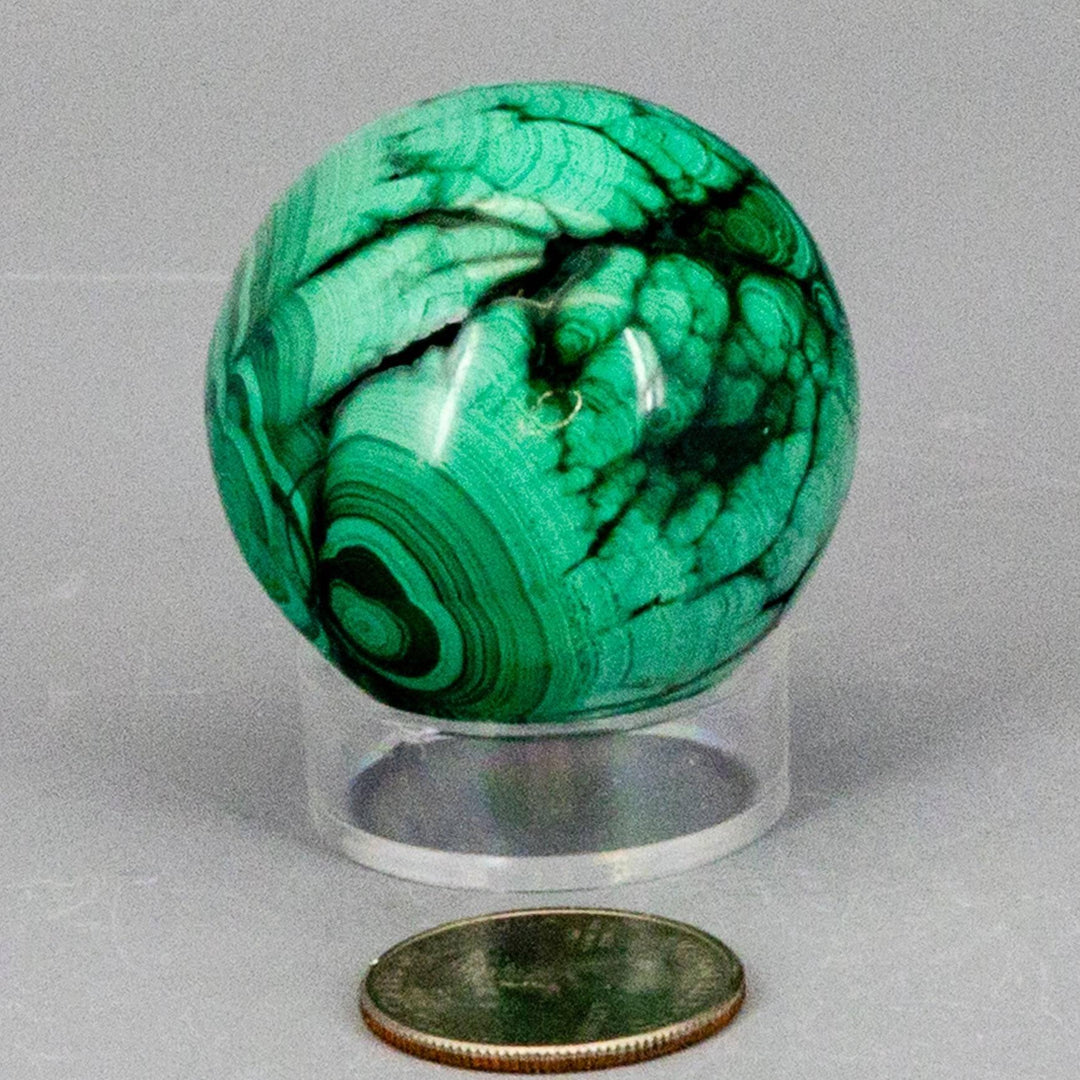 Visually commanding Malachite Sphere with deep forest green and mint concentric banding, radiating protective healing energy.