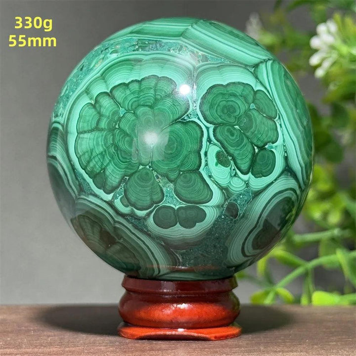 Polished 55mm Malachite crystal sphere featuring deep green banded patterns, perfect for healing and transformation.
