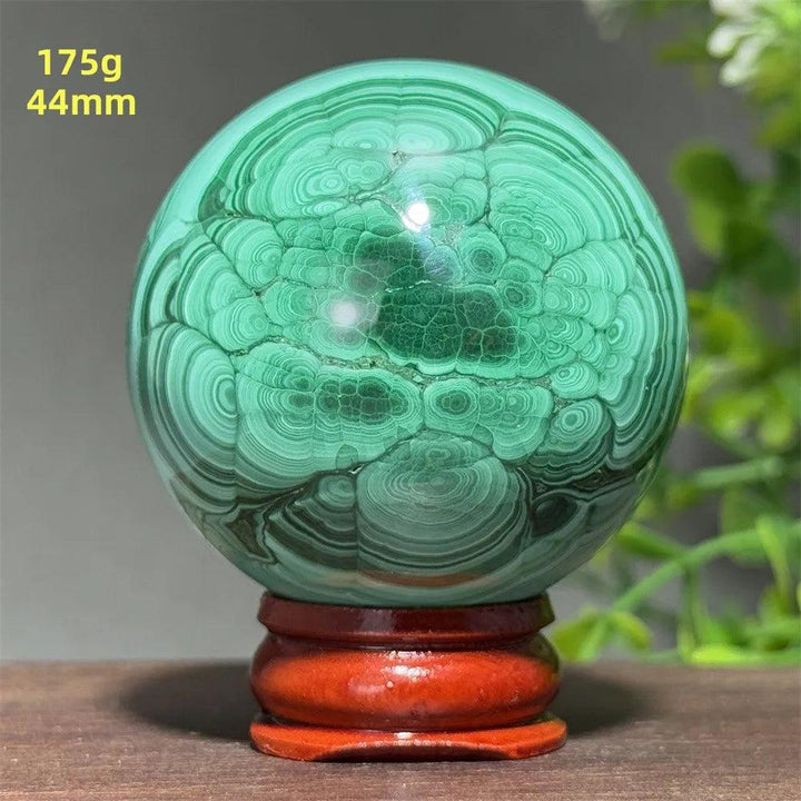 44mm AAAAA Malachite crystal sphere with deep green concentric banding on a wooden display base for healing energy.