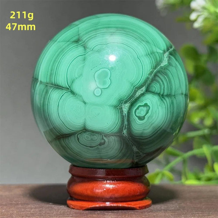 Polished 47mm Malachite crystal sphere featuring vibrant green concentric banding on a wooden display base for healing.