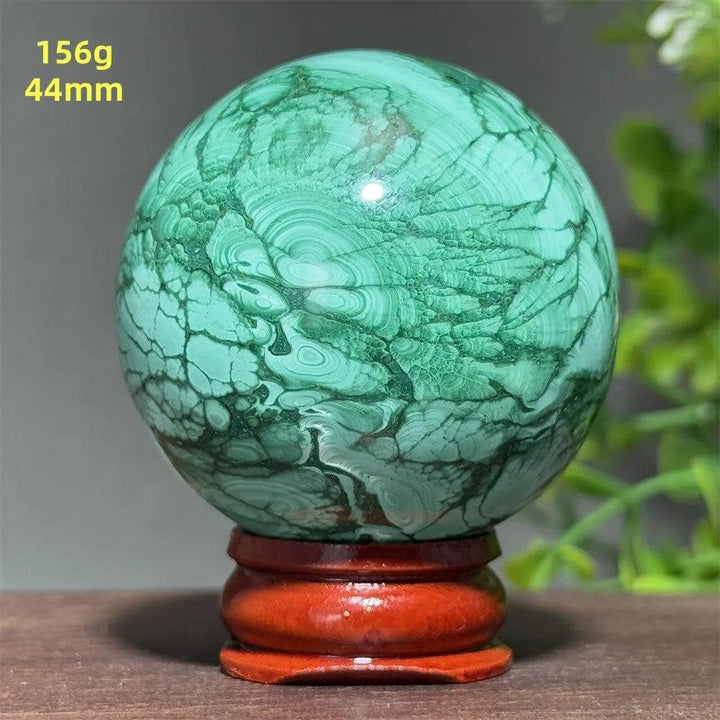 AAAAA grade 44mm Malachite crystal sphere featuring deep green banded patterns on a wooden display base for healing.