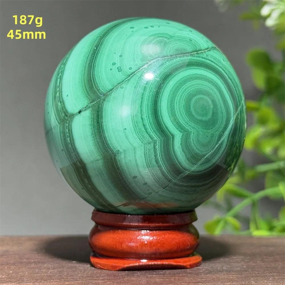 45mm Malachite crystal sphere featuring deep green banded patterns for healing and transformation on a display base.