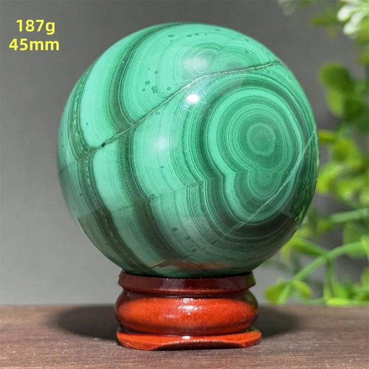 45mm Malachite crystal sphere featuring deep green banded patterns for healing and transformation on a display base.