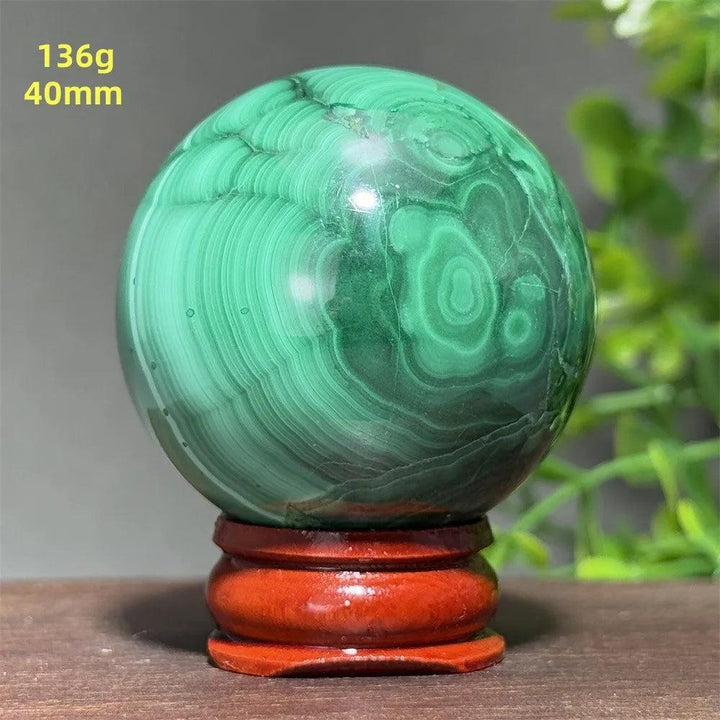 40mm AAAAA Malachite crystal sphere featuring deep green banded patterns on a wooden display base for healing energy.