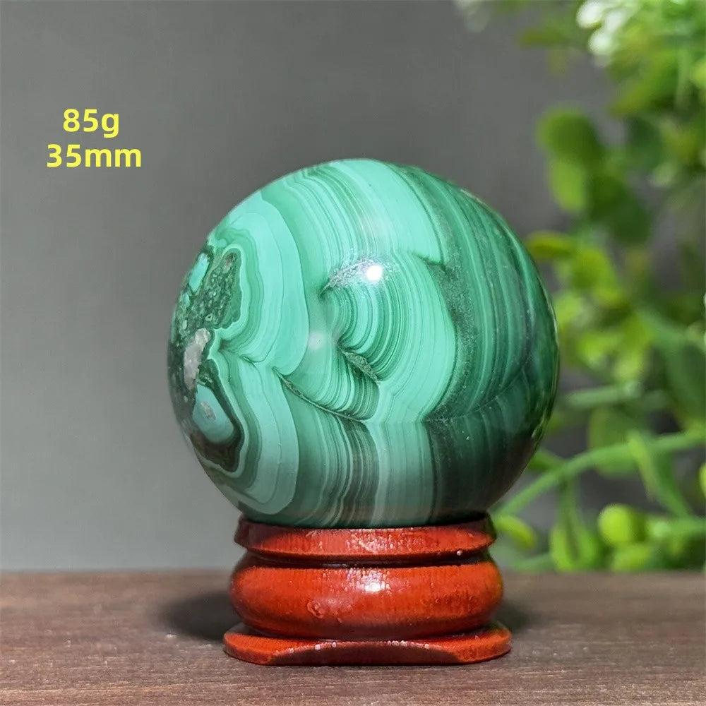 Polished 35mm Malachite crystal sphere featuring deep green banded patterns on a wooden display base for healing energy.