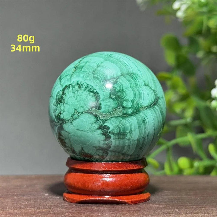 Polished 34mm Malachite crystal sphere featuring deep green banded patterns on a wooden display base for healing.