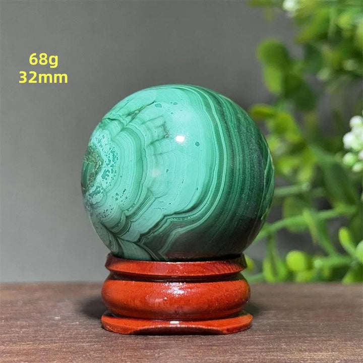 Polished 32mm Malachite crystal sphere featuring deep green banded patterns on a wooden display base for healing.