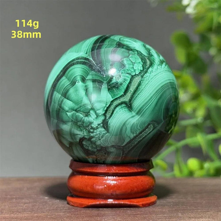 Polished 38mm malachite crystal sphere featuring deep green banded patterns on a wooden display base for healing energy.