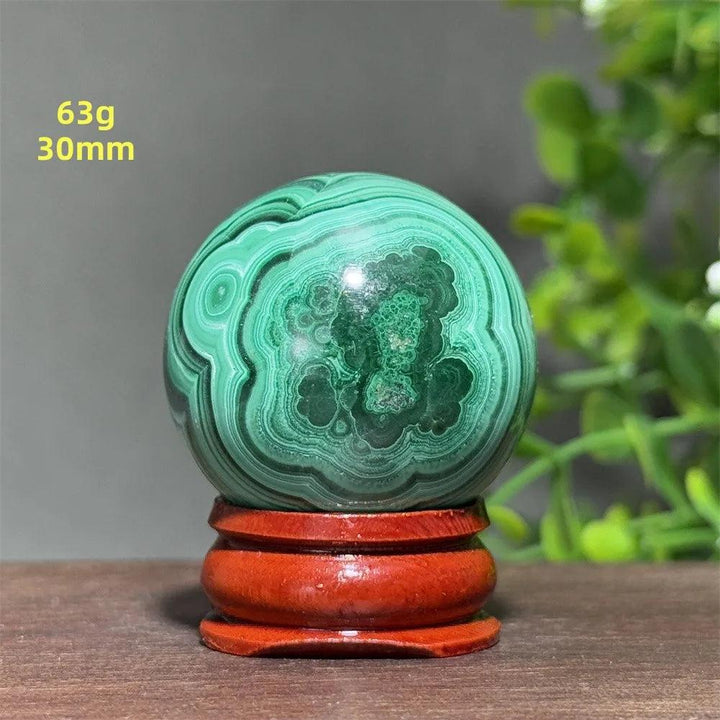 Polished 30mm Malachite crystal sphere featuring vibrant green banded patterns on a wooden display base for healing.