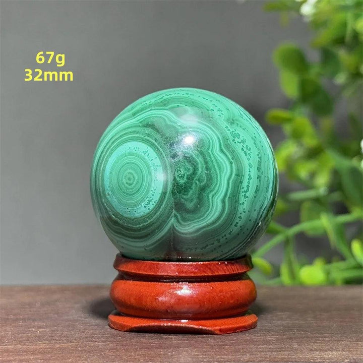 Polished 32mm Malachite crystal sphere featuring deep green banded patterns on a wooden display base for healing.