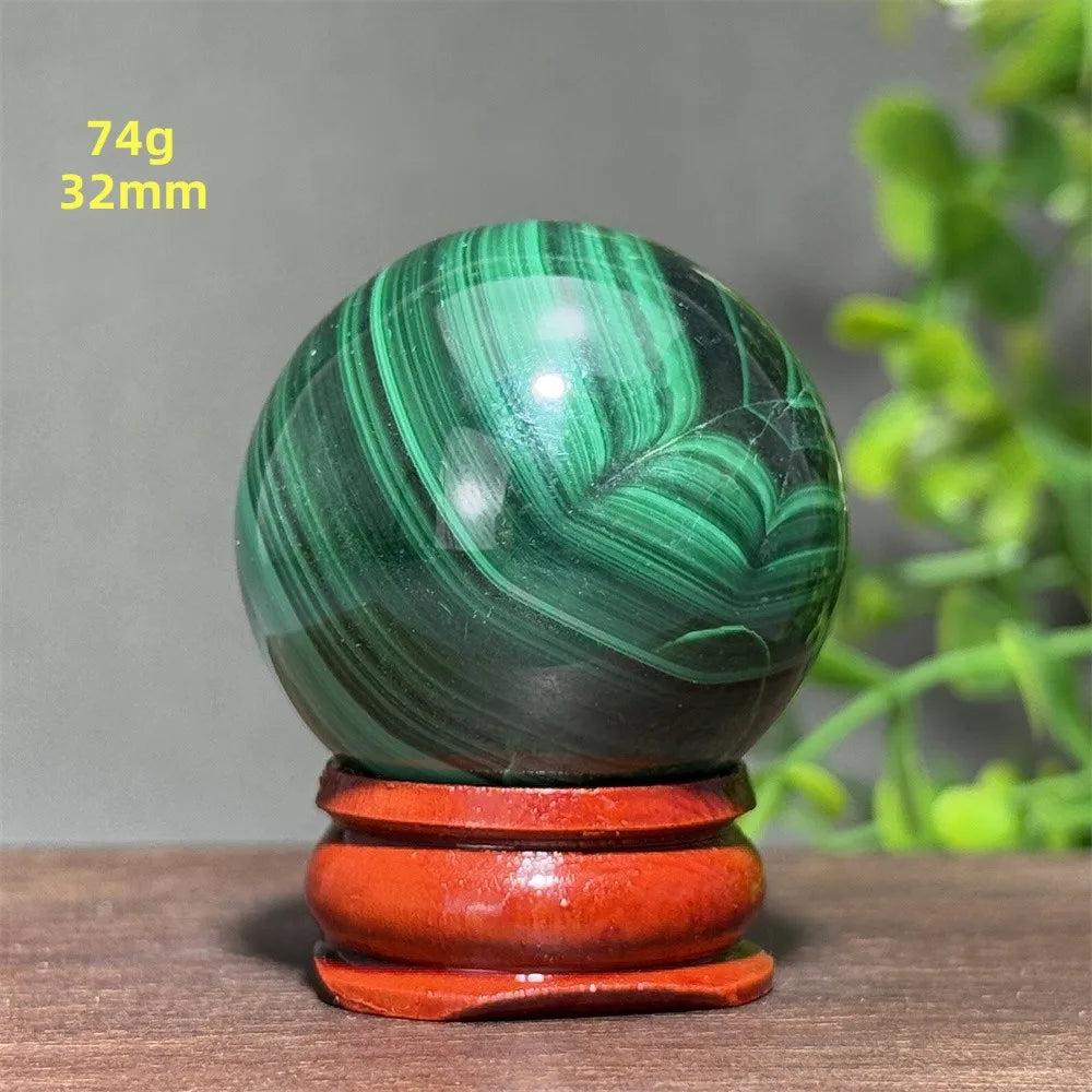 Polished 32mm Malachite crystal sphere featuring deep green banded patterns on a wooden display base for healing.
