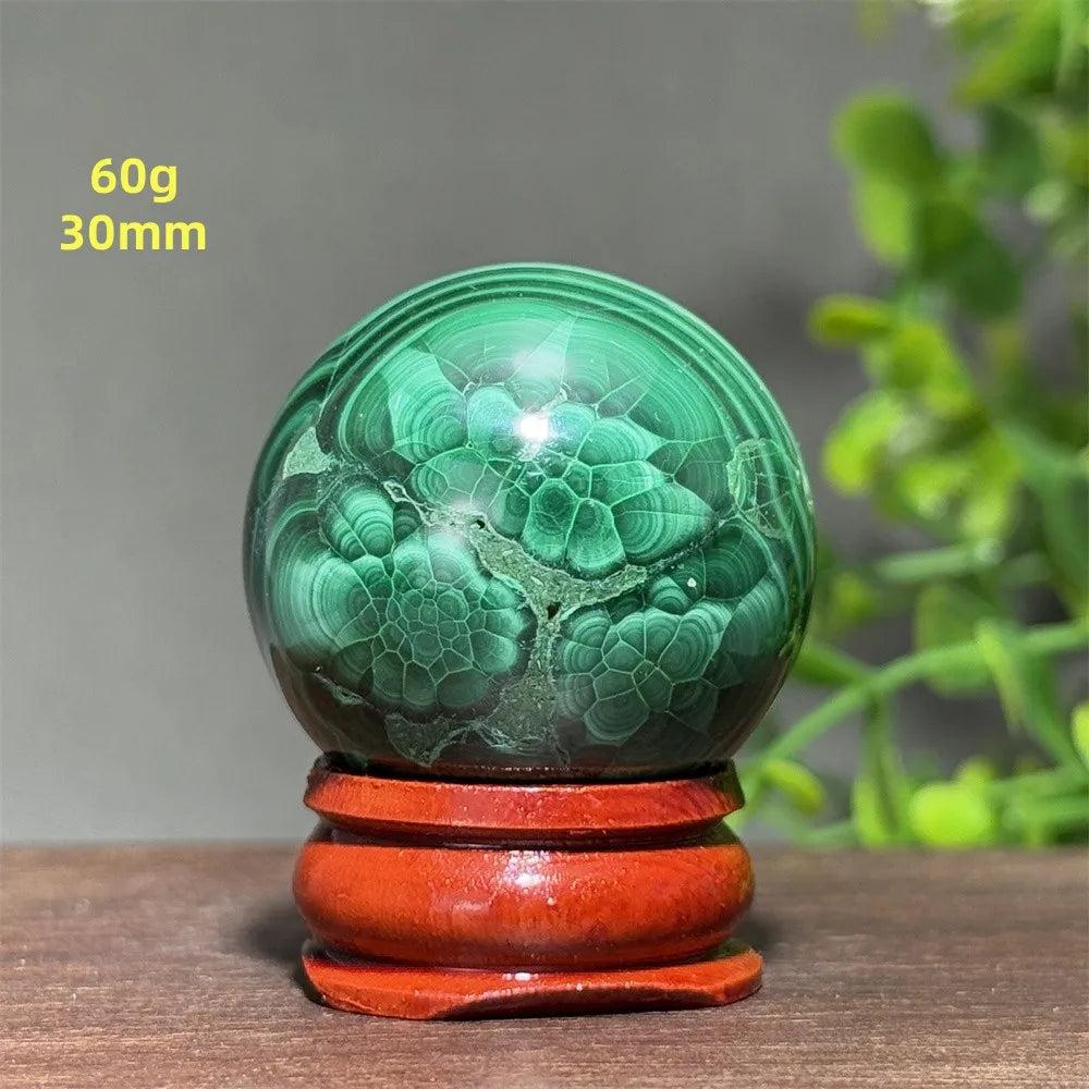 Polished 30mm Malachite crystal sphere featuring deep green banded patterns on a wooden display base for healing.