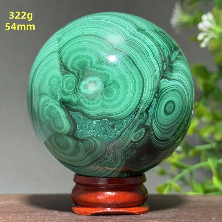 Polished 54mm Malachite crystal sphere featuring deep green banded patterns for transformation and healing on a display base.