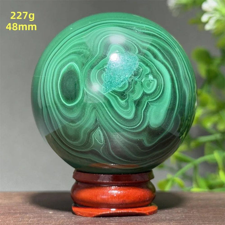 AAAAA grade 48mm malachite crystal sphere featuring deep green banded patterns on a wooden display base for healing.