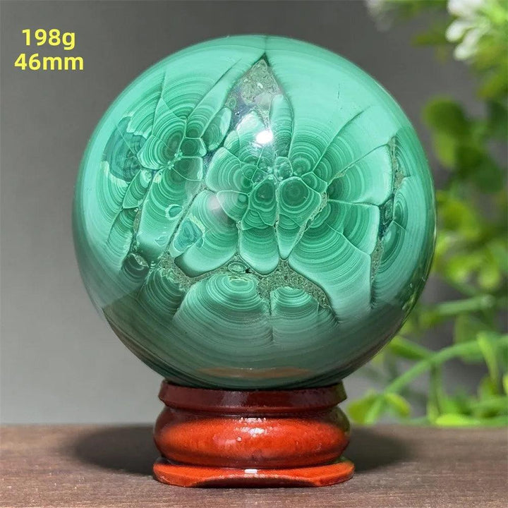 46mm Malachite crystal sphere featuring deep green banded patterns for transformation, displayed on a wooden base.