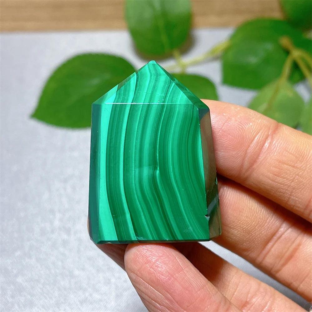 Handheld Malachite Crystal Tower with vibrant green banded patterns, perfect for heart chakra healing and transformation.