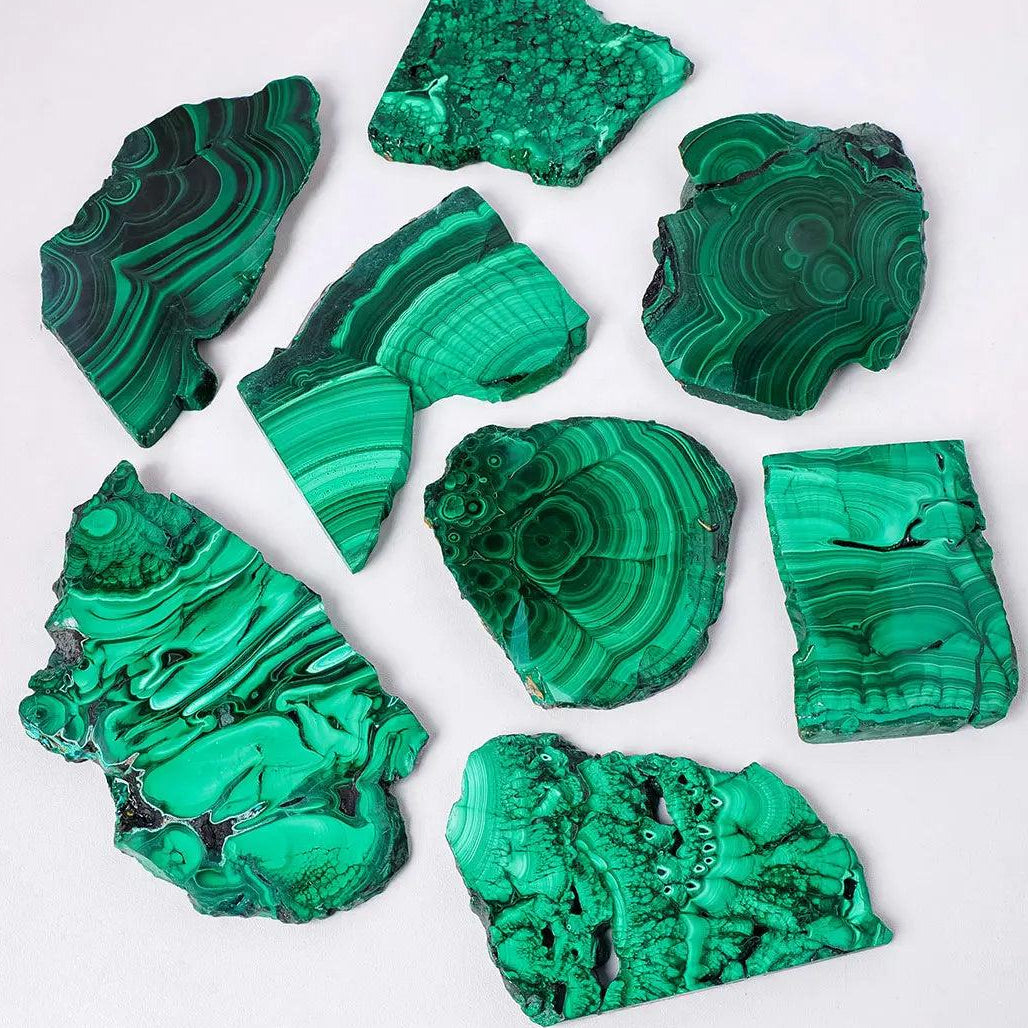 Raw malachite pieces featuring vivid green bands and eye-like rings, perfect for heart chakra healing and home decor.