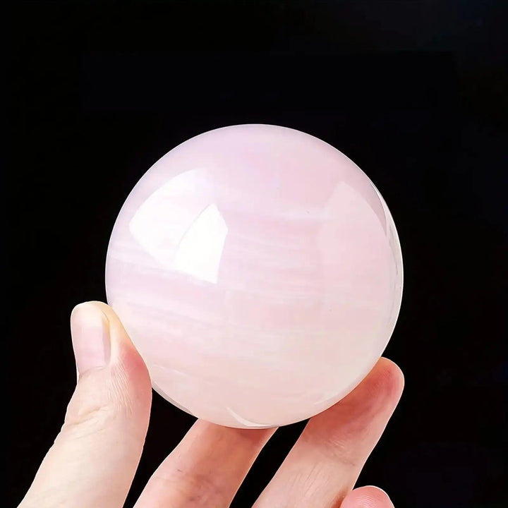 Hand-polished Mangano Calcite sphere in soft pastel pink with creamy white banding for Heart chakra healing and compassion.