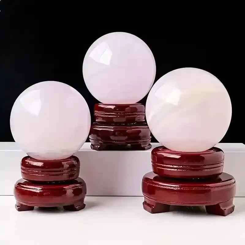 Polished pastel pink Mangano Calcite spheres on wooden stands, perfect for Heart chakra healing and emotional ease.