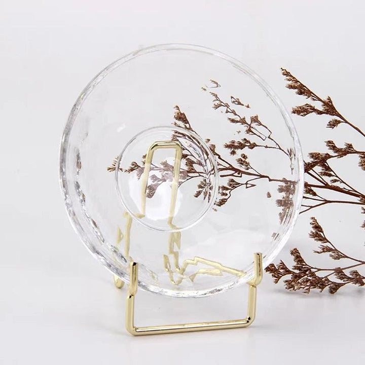 Clear crystal sphere on a small gold metal arm easel stand, with dried foliage in the background.
