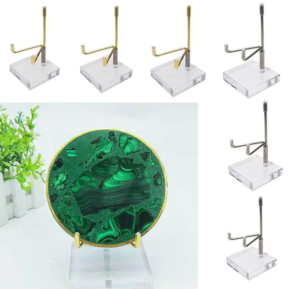 Gold and silver metal crystal ball display stands with clear acrylic bases, holding a vibrant green malachite sphere.