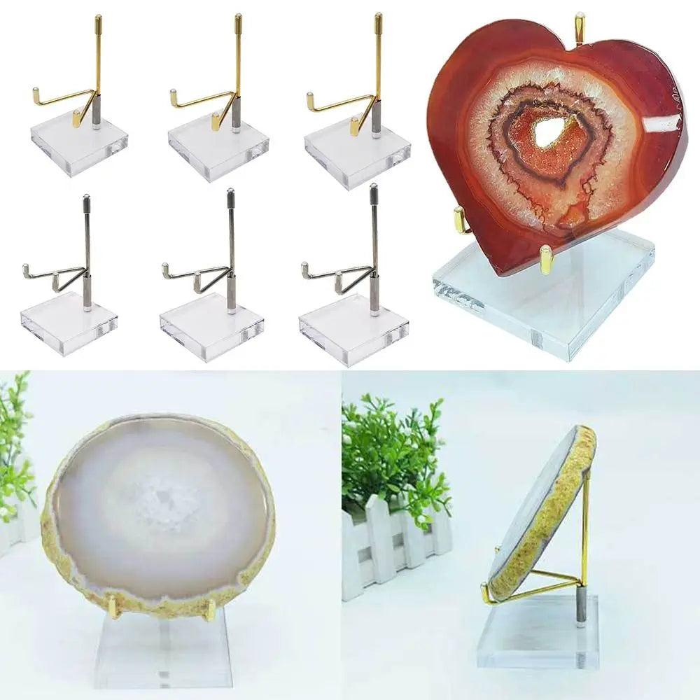 Gold and silver metal display stands with clear acrylic bases holding a red heart-shaped agate and a round white agate.