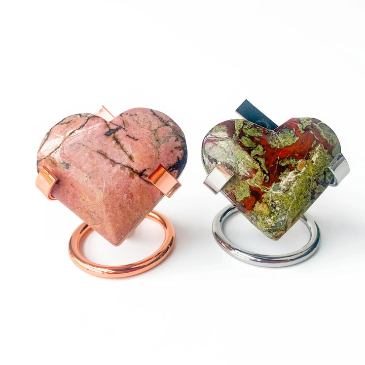 Rose gold and silver metal heart stands displaying pink rhodonite and green dragon's blood jasper heart stones.