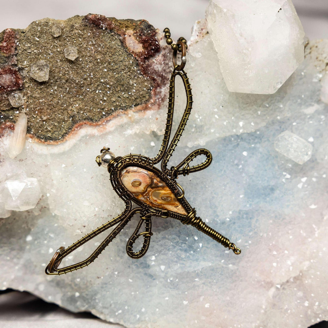 Handcrafted copper wire dragonfly pendant with a banded Mexican Agate crystal, symbolizing transformation and grounding.