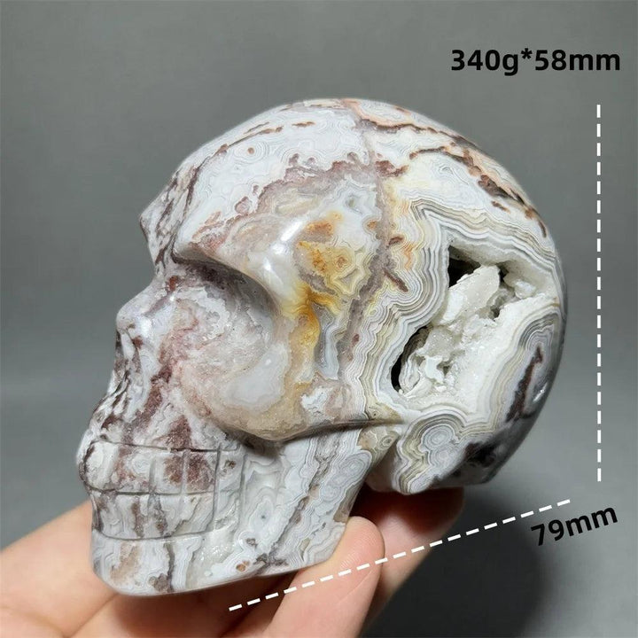 Hand-carved Mexican Agate skull with white, brown, and orange bands, featuring a crystal geode opening.