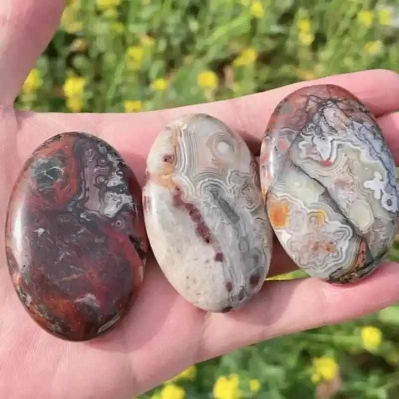 Three polished Mexican Red Agate palm stones with intricate banding and earthy colors, perfect for healing and home decor.