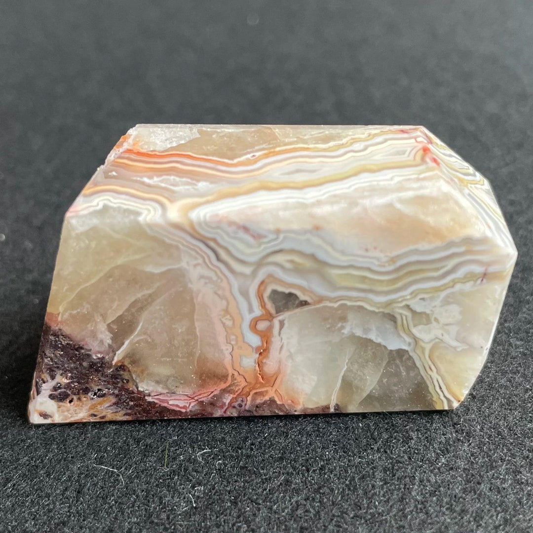 Polished Mexico Agate freeform crystal with banded tan, white, and red carnelian patterns for Reiki healing and decor.