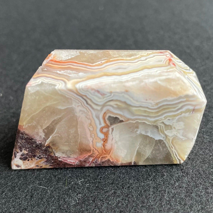 Polished Mexico Agate freeform crystal with banded tan, white, and red carnelian patterns for Reiki healing and decor.