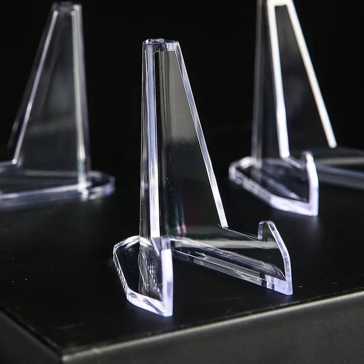 Clear acrylic triangle easel stands for crystals, 54x35mm, on a dark surface.