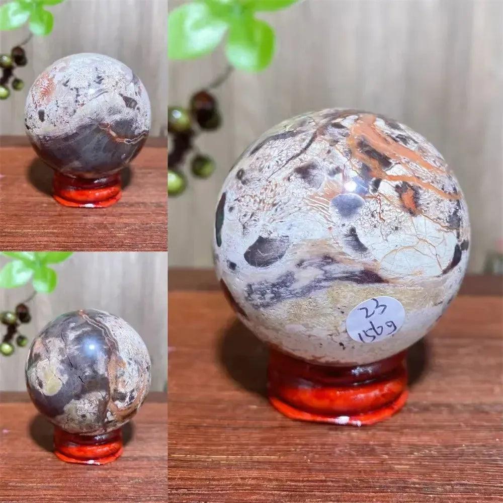 Polished Money Agate Crystal Sphere, a unique abundance stone with gold, rust, and cream banding on a red stand.