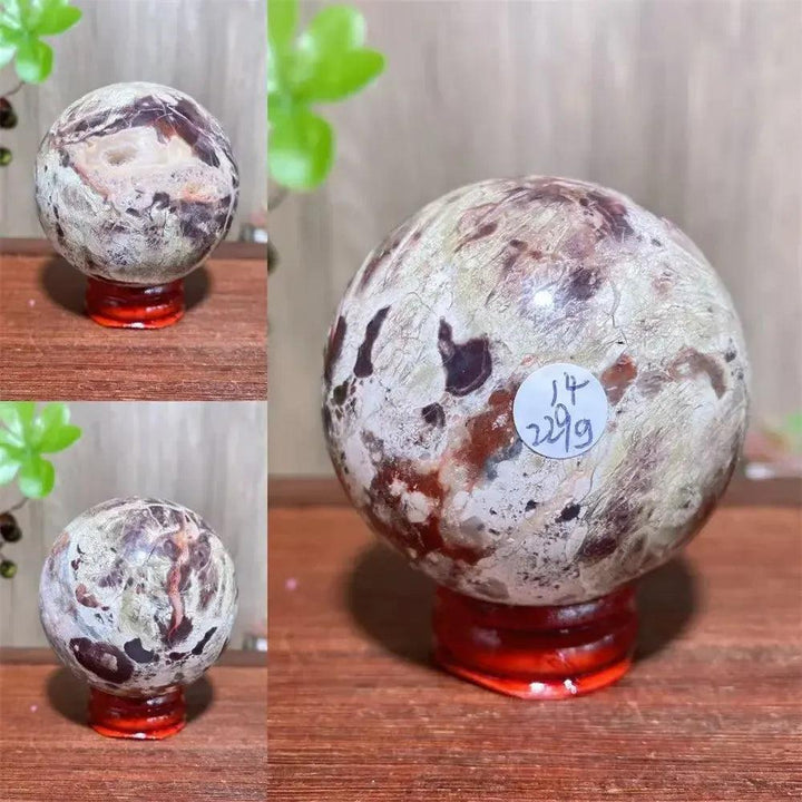 Money Agate Crystal Sphere Polished Abundance Stone with gold, rust, cream, and warm brown banding on a red stand.