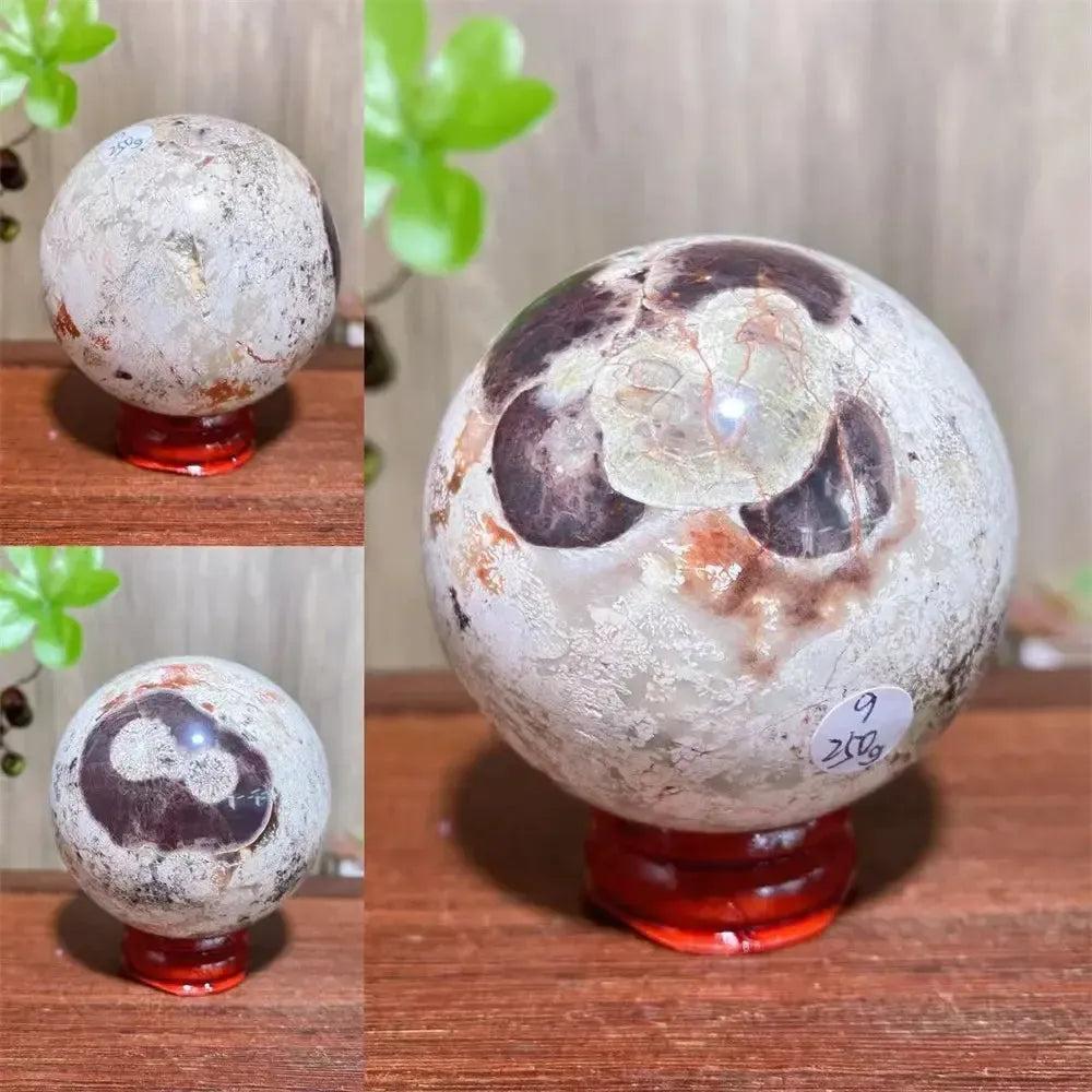 Polished Money Agate Crystal Sphere, a unique abundance stone with gold, rust, and cream banding on a red stand.