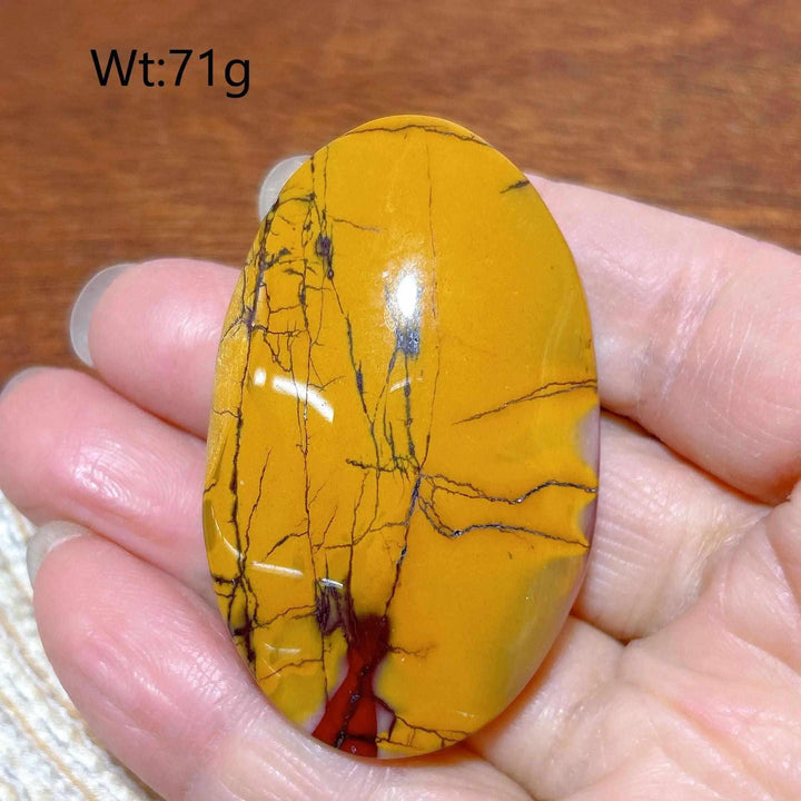 Smooth, mustard yellow Mookaite Jasper palm stone with red accents, perfect for grounding and boosting vitality.